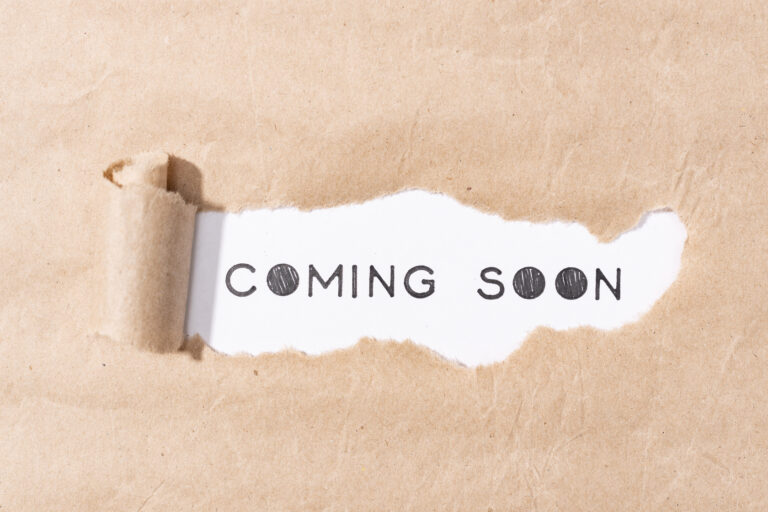 Coming soon message on torn paper. White and brown paper